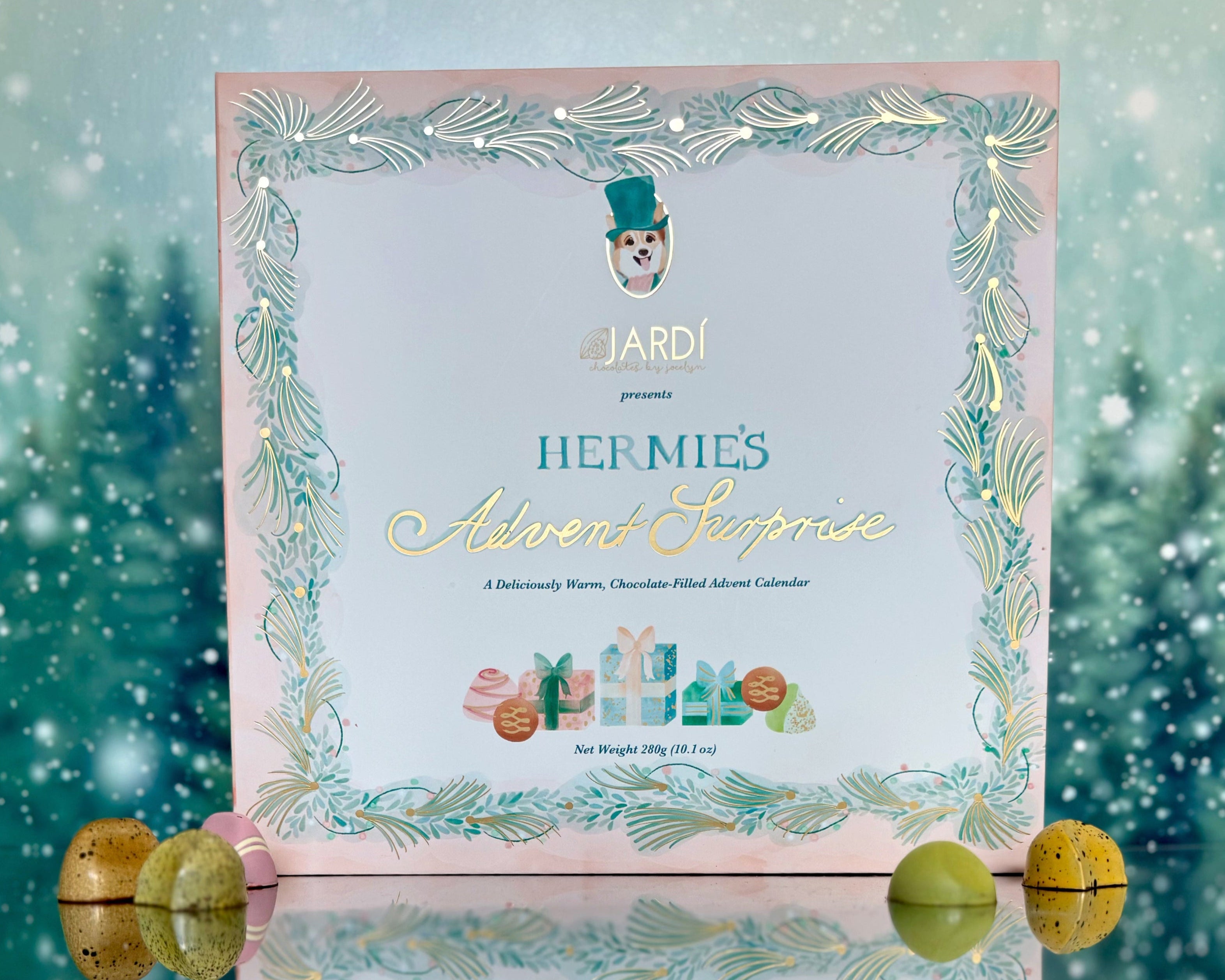 Hermes Advent Calendar with decorative border on a reflective surface with blurred greenery in the background